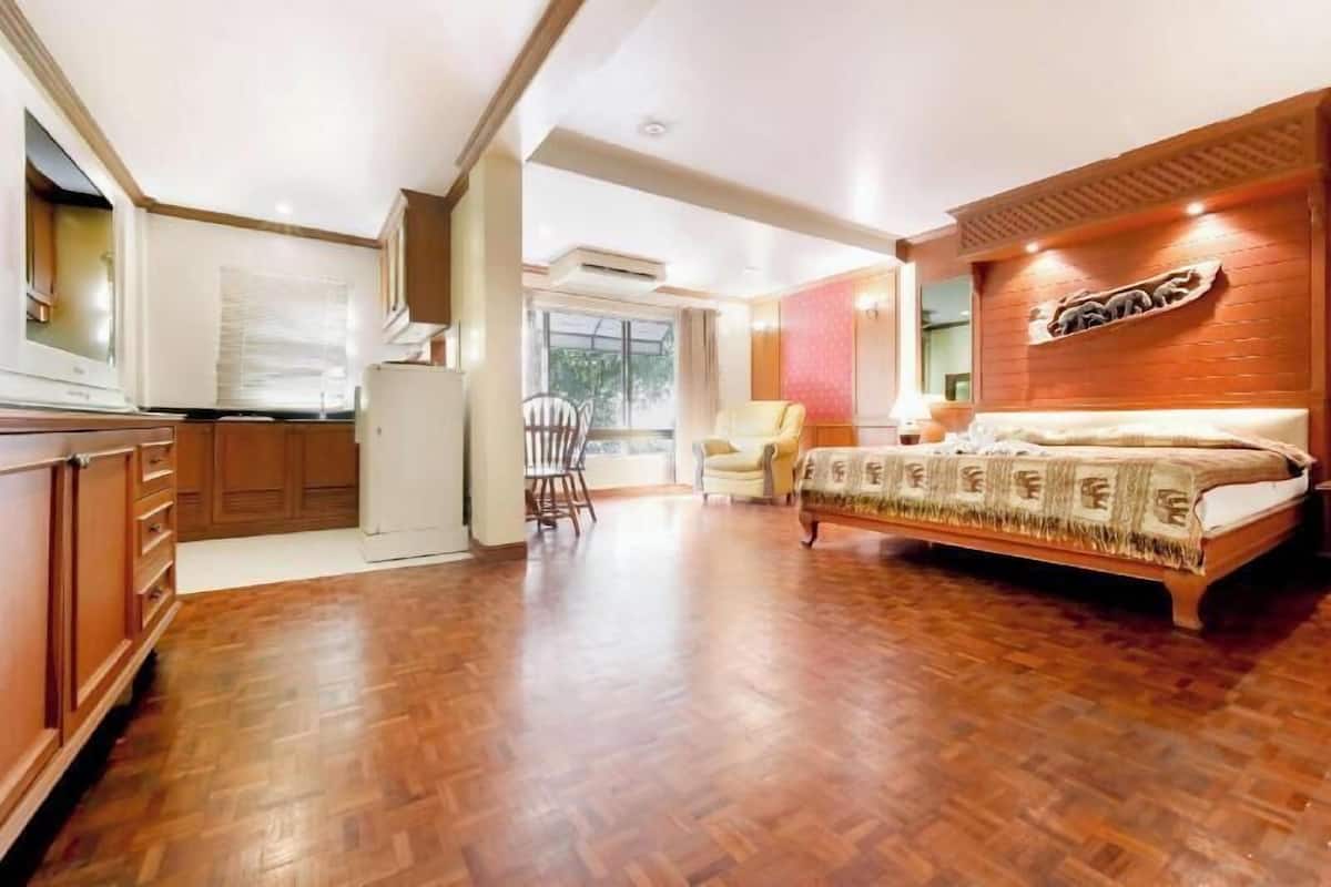 Une chambre à coucher avec un lit, une armoire en bois, une chaise et une fenêtre.