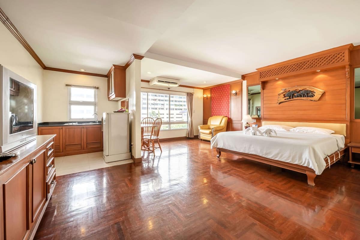 Une chambre d’hôtel avec un plancher en bois, un lit, une télévision, un coin cuisine et une vue sur l’extérieur.