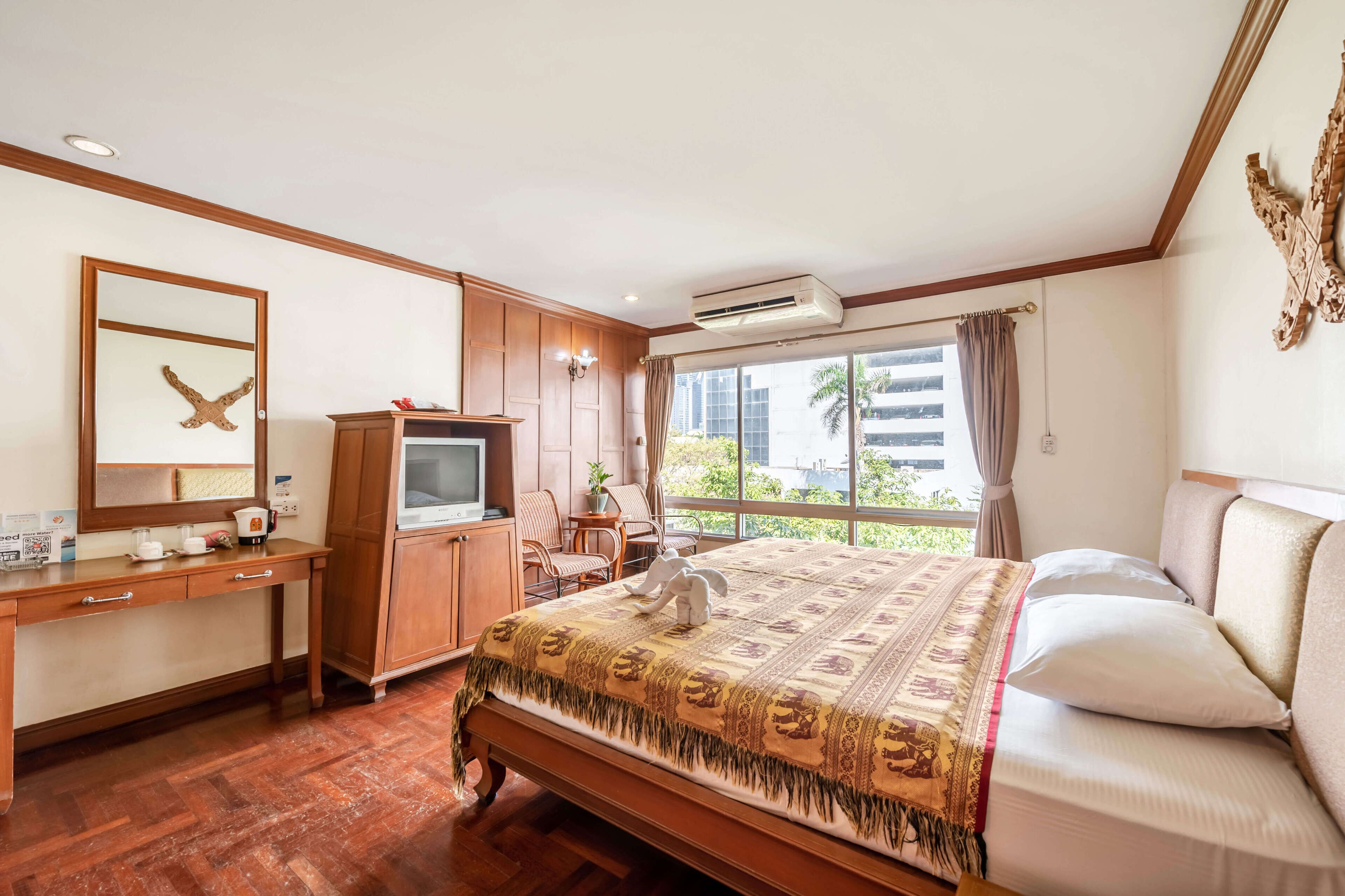 Een hotelkamer met een bed, bureau, televisie en een groot raam.