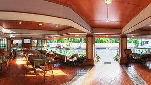 A spacious indoor area with multiple dining tables and chairs, a central open space, and large windows providing natural light and views of the outdoors.