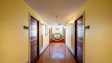 Un pasillo de hotel con puertas de madera, una recepción y suelo de baldosas.