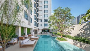 Een modern hotel met een zwembad, terras en groen.