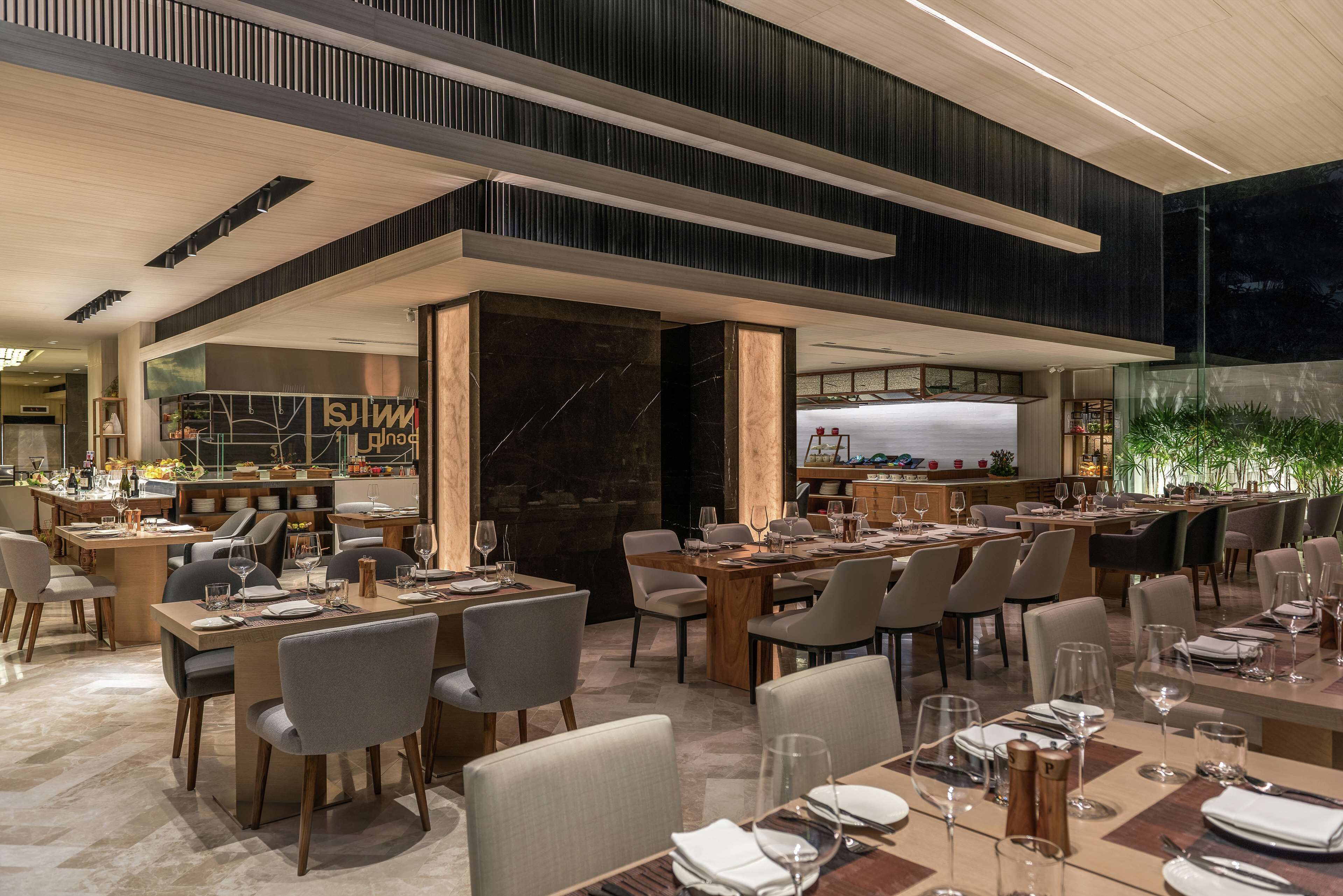 A modern restaurant with multiple dining areas, a bar, and a visible kitchen.