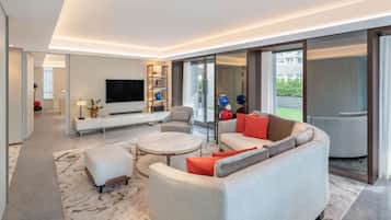 A modern living room with a flat-screen TV, a sofa, a coffee table, and a dining area.