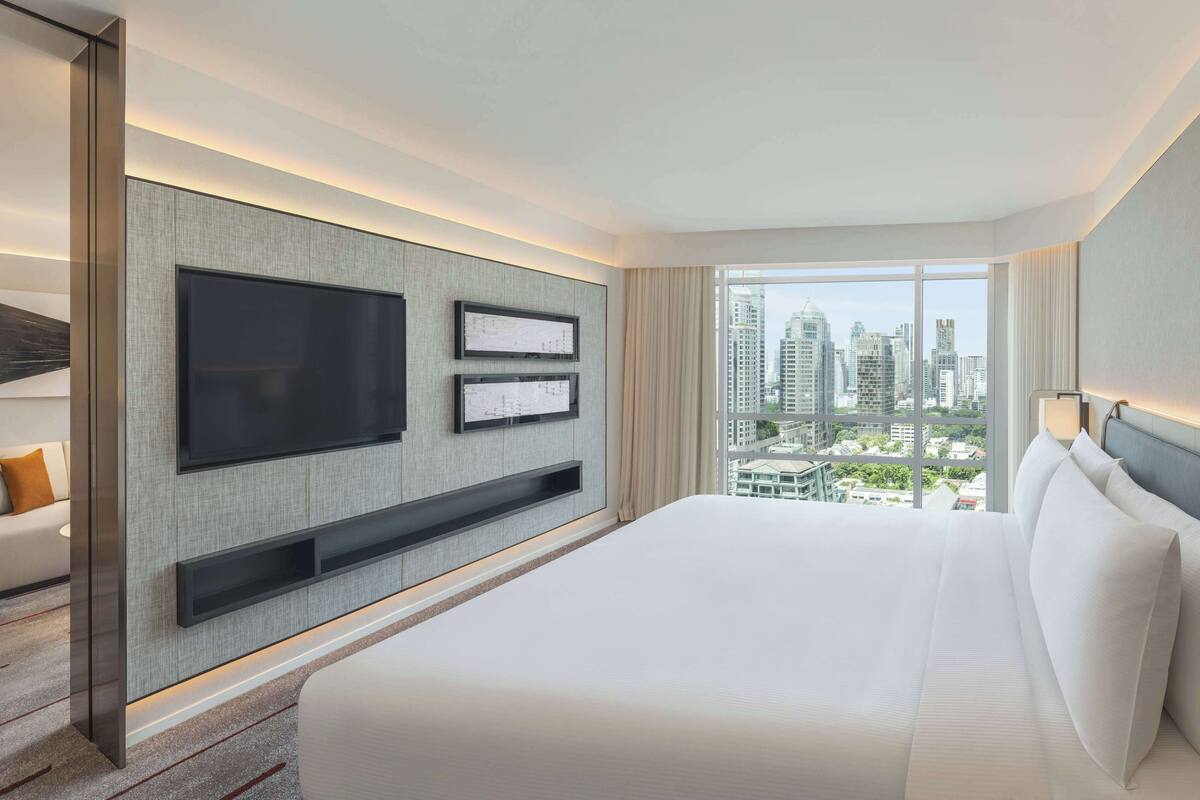 Une chambre d’hôtel moderne dotée d’un grand lit, d’une télévision à écran plat et offrant une vue sur la ville.