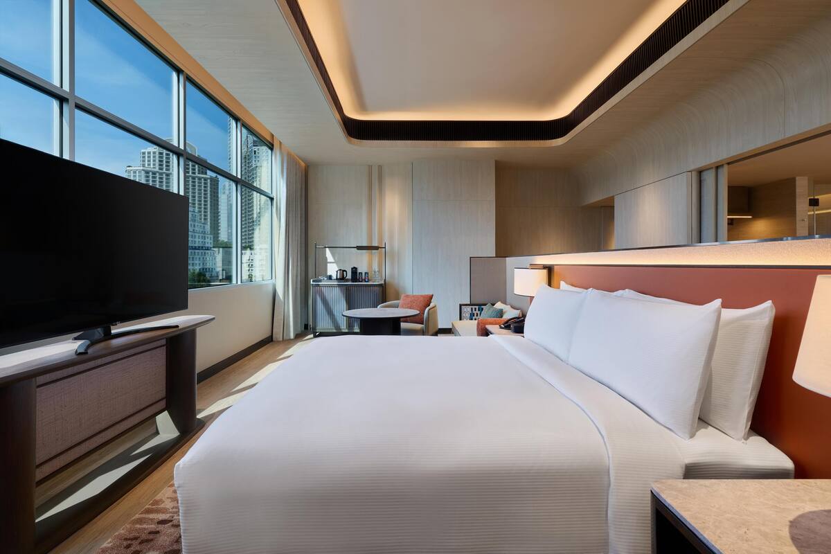 Une chambre d’hôtel moderne équipée d’un grand lit, d’un téléviseur à écran plat, d’un bureau et d’une chaise.