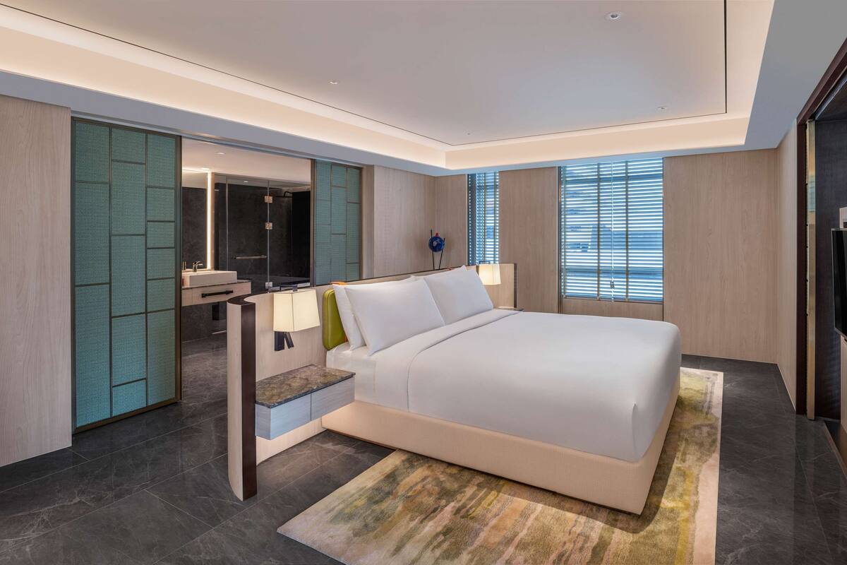 Une chambre moderne avec un grand lit, une coiffeuse intégrée, un miroir et un téléviseur.