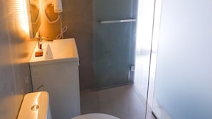 Une salle de bain moderne équipée de toilettes, d’un lavabo et d’une douche à parois de verre.