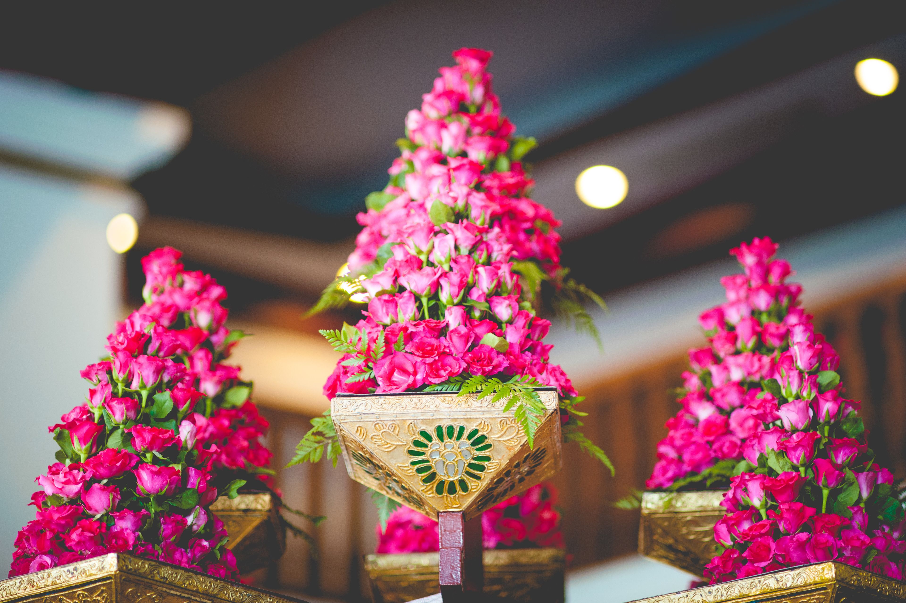A series of ornate, gold-framed flower stands with pink flowers.