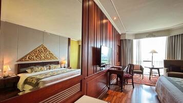 A hotel room with a large bed, a desk, a chair, and a sofa.