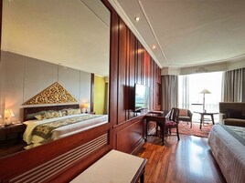 A hotel room with a large bed, a desk, a chair, and a sofa.