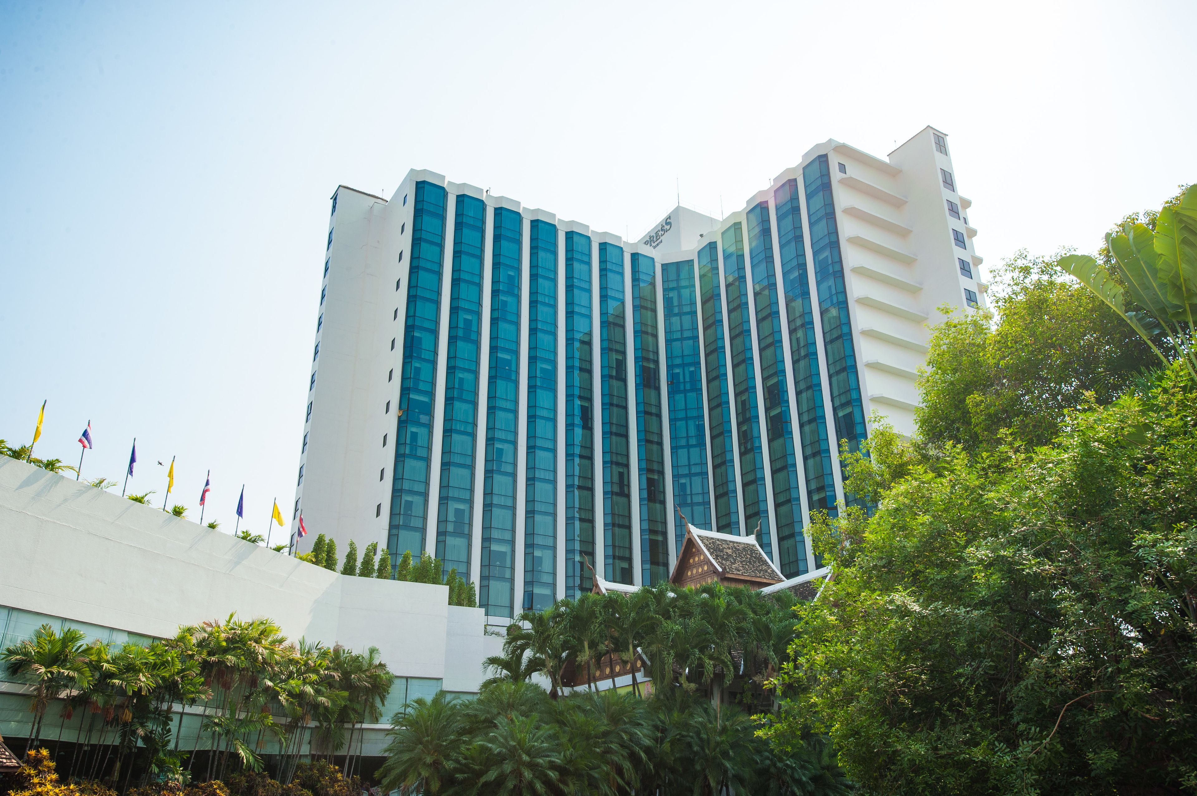 Un hotel moderno con una estructura de gran altura, que destaca por su fachada de vidrio y un elemento arquitectónico tradicional en la base.