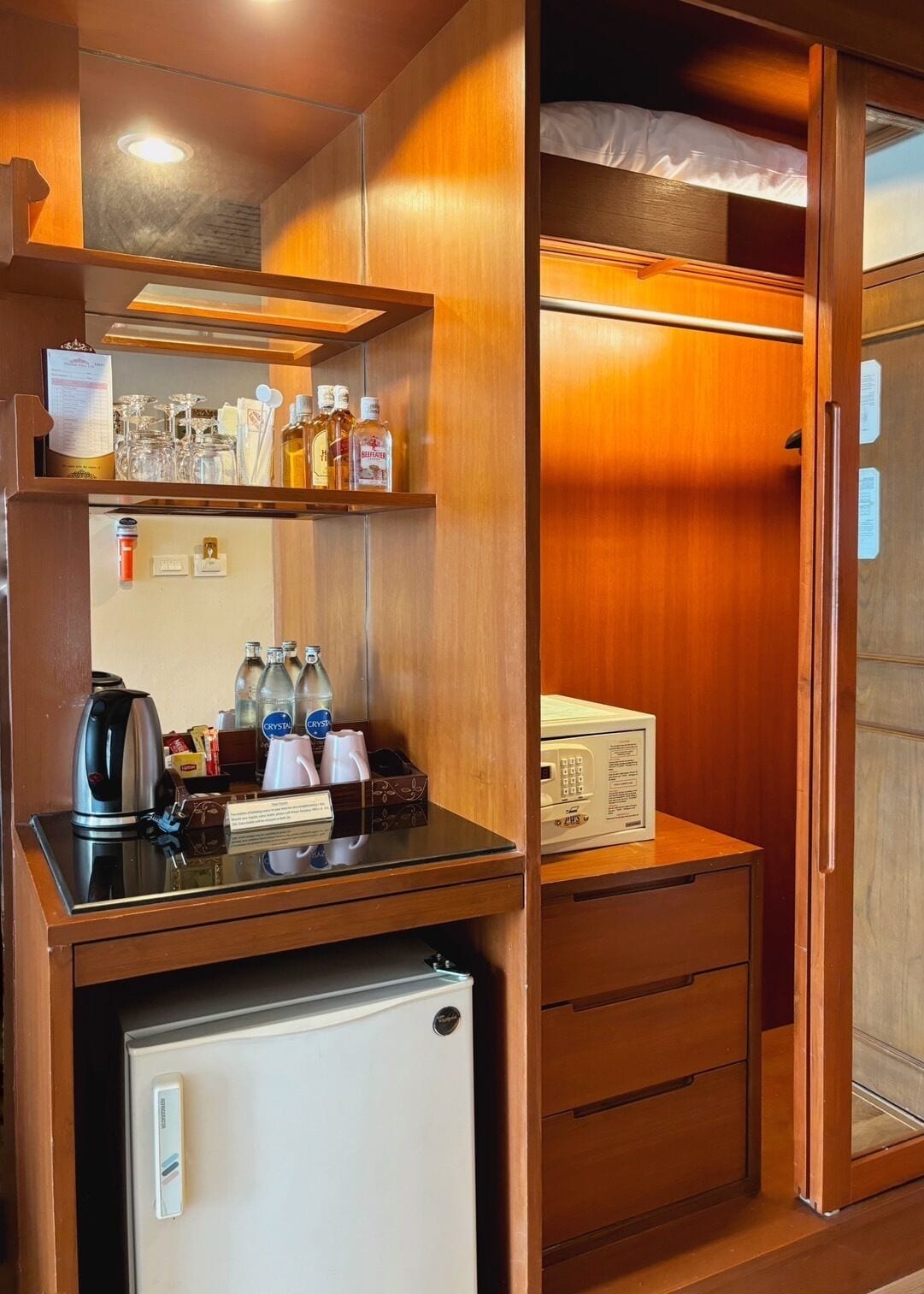 A compact kitchenette with a coffee maker, kettle, and microwave, and a small refrigerator.