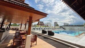 Un espace piscine aménagé sur le toit, avec des meubles en bois et une vue sur le panorama urbain.