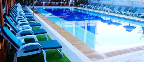 A pool area with lounge chairs and umbrellas.