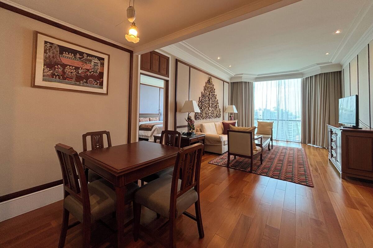 Uma sala de estar ampla, com área de jantar, uma janela grande com vista e uma televisão.