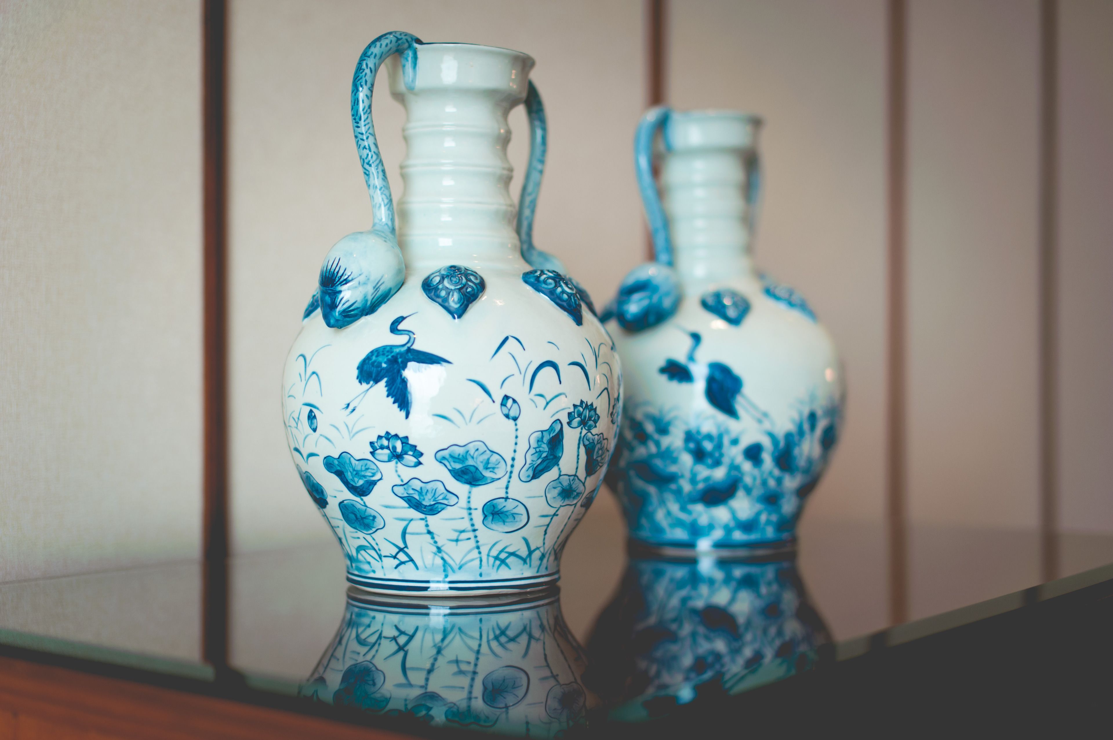 Two ceramic vases with blue floral designs on a reflective surface.