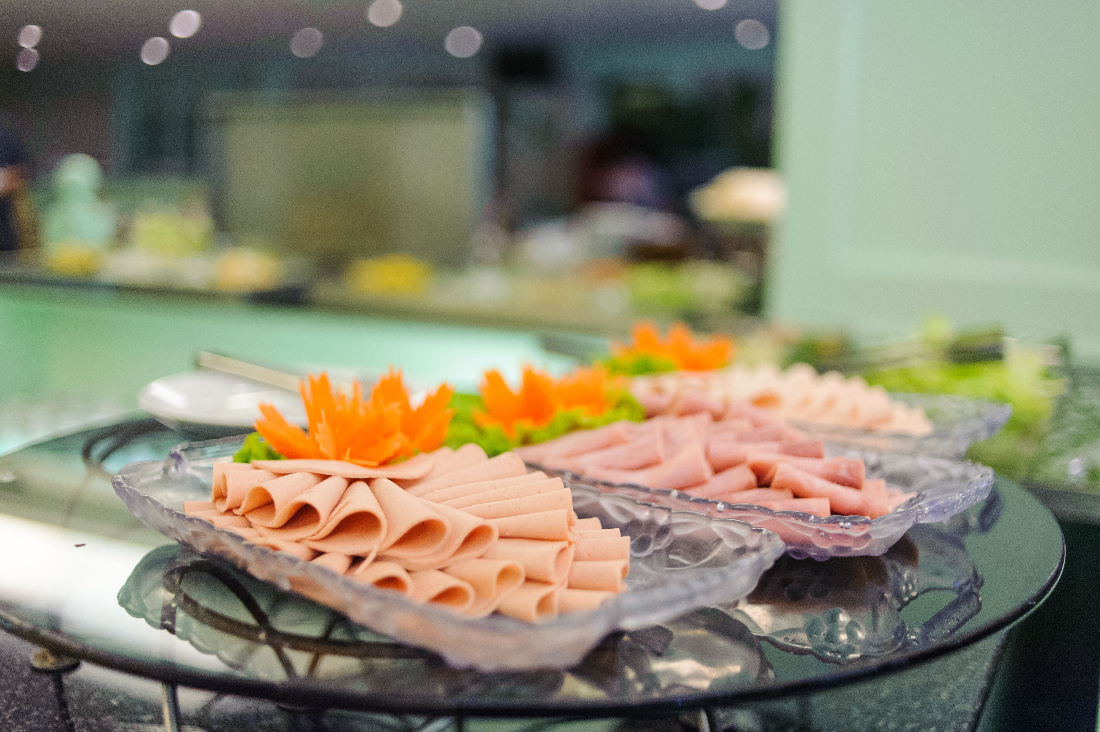 A buffet table with neatly arranged food items, including sliced meats and garnished with orange flowers.
