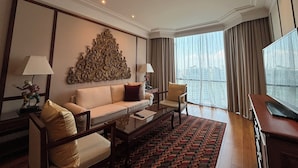 Une chambre d’hôtel moderne équipée d’un canapé, de fauteuils, d’une table basse et d’un téléviseur.