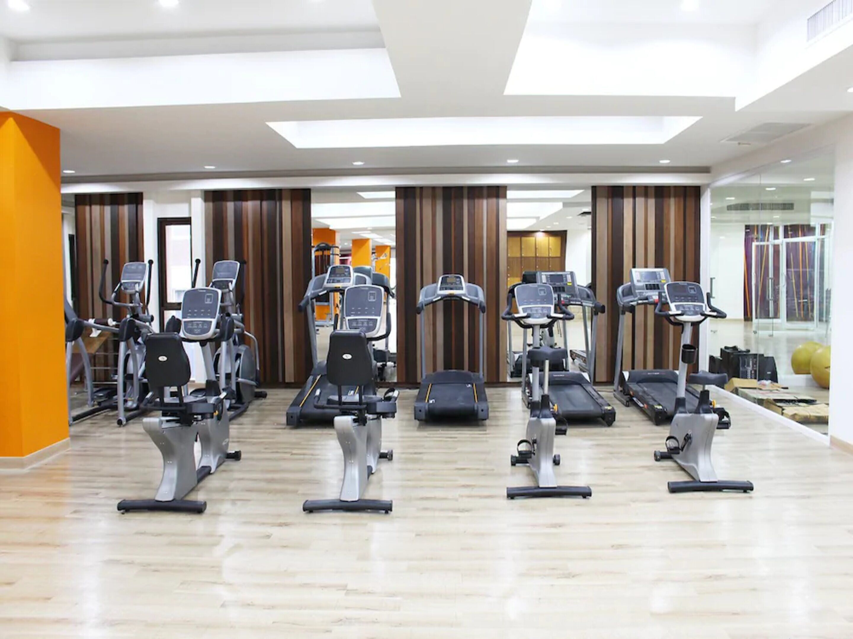 A modern gym with multiple treadmills, stationary bikes, and elliptical machines.