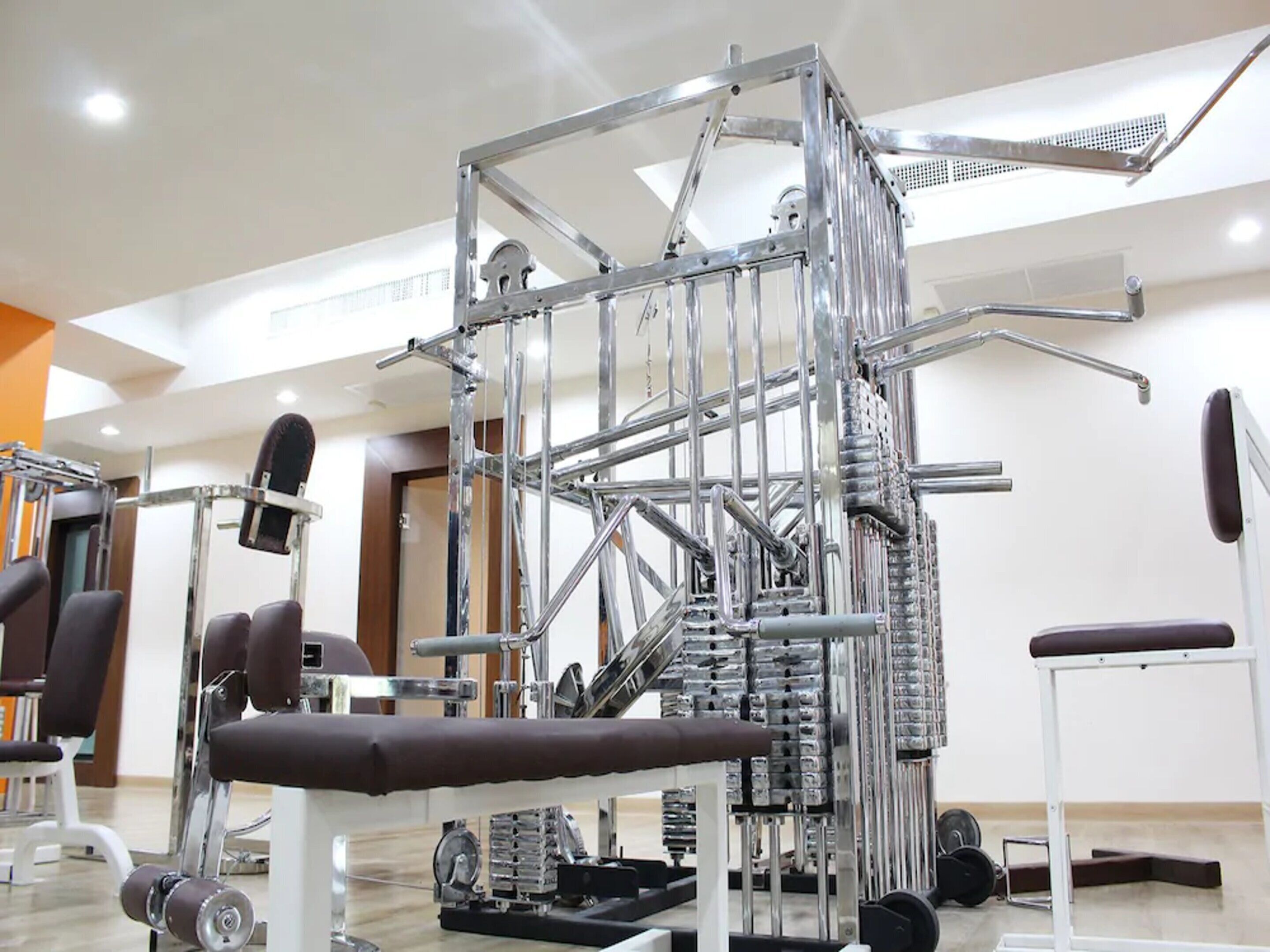 A gym with various exercise equipment, including a multi-level cable machine and weight stacks.