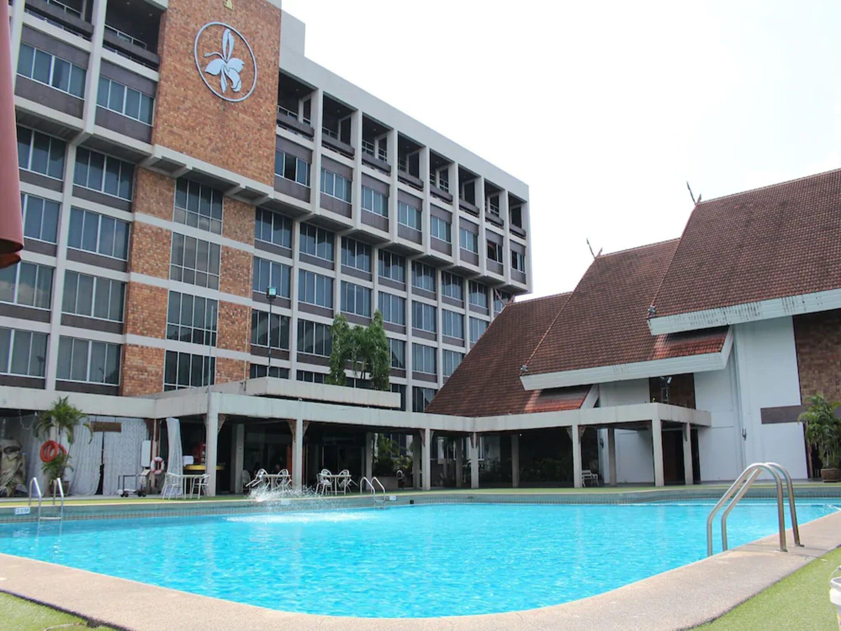 Un hotel con piscina, varios pisos y un logotipo distintivo en el edificio.