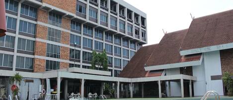 Un hotel con piscina, varios pisos y un logotipo distintivo en el edificio.