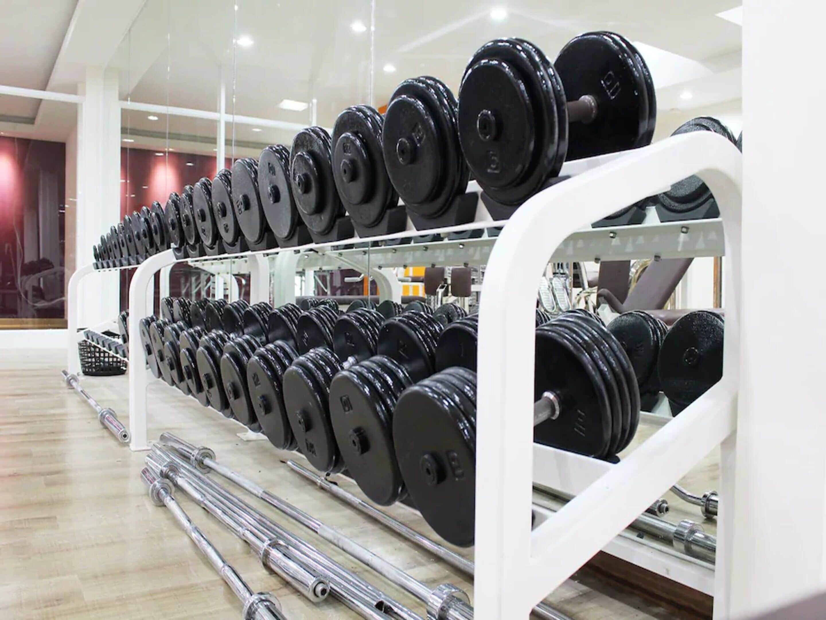 A gym with rows of barbells and dumbbells on racks.