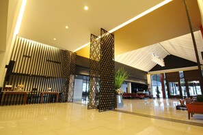 Un vestíbulo amplio con diseño moderno, que incluye una recepción, zona de estar y paneles decorativos.