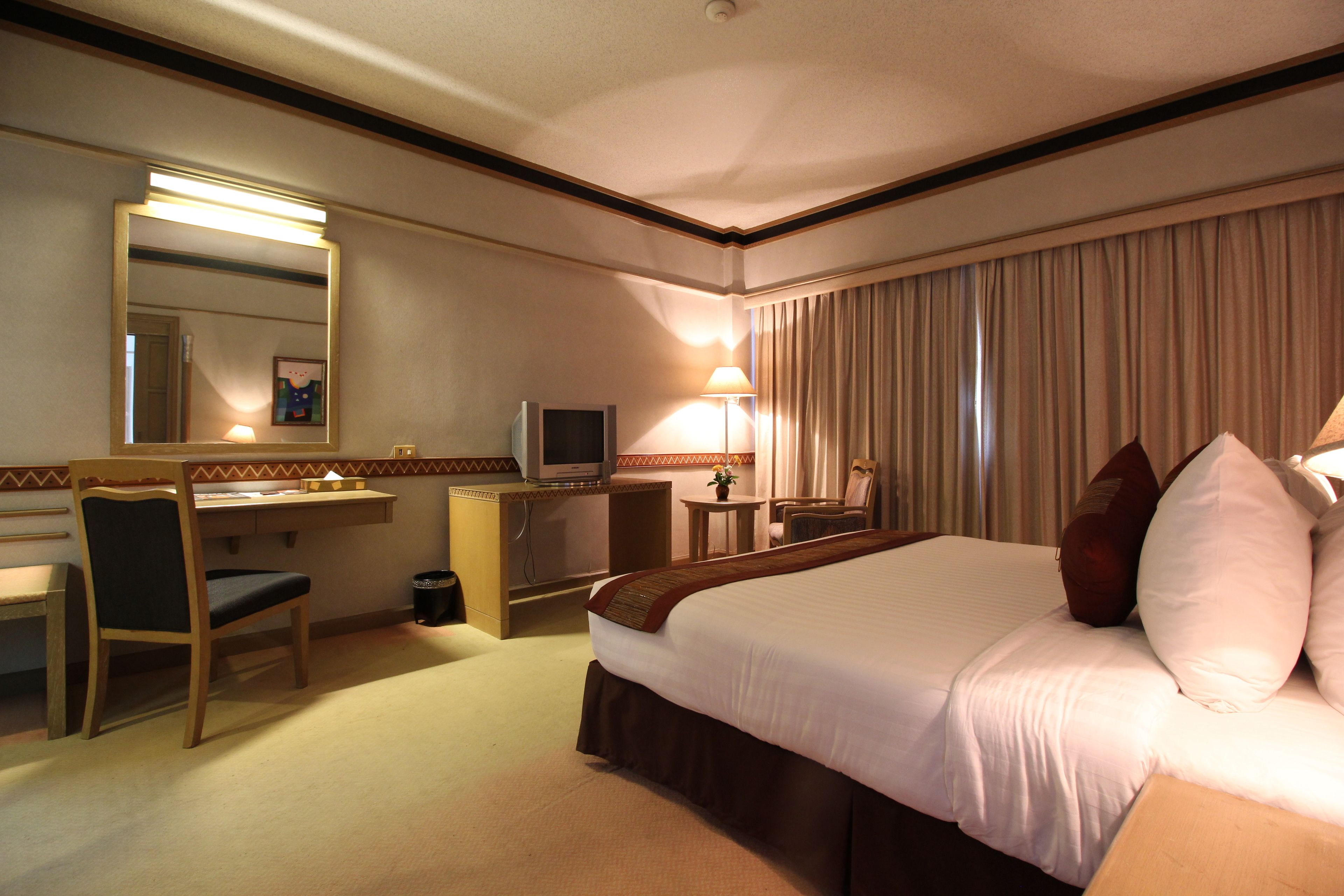 Een hotelkamer met een bed, een bureau, een stoel, een televisie en een lamp.