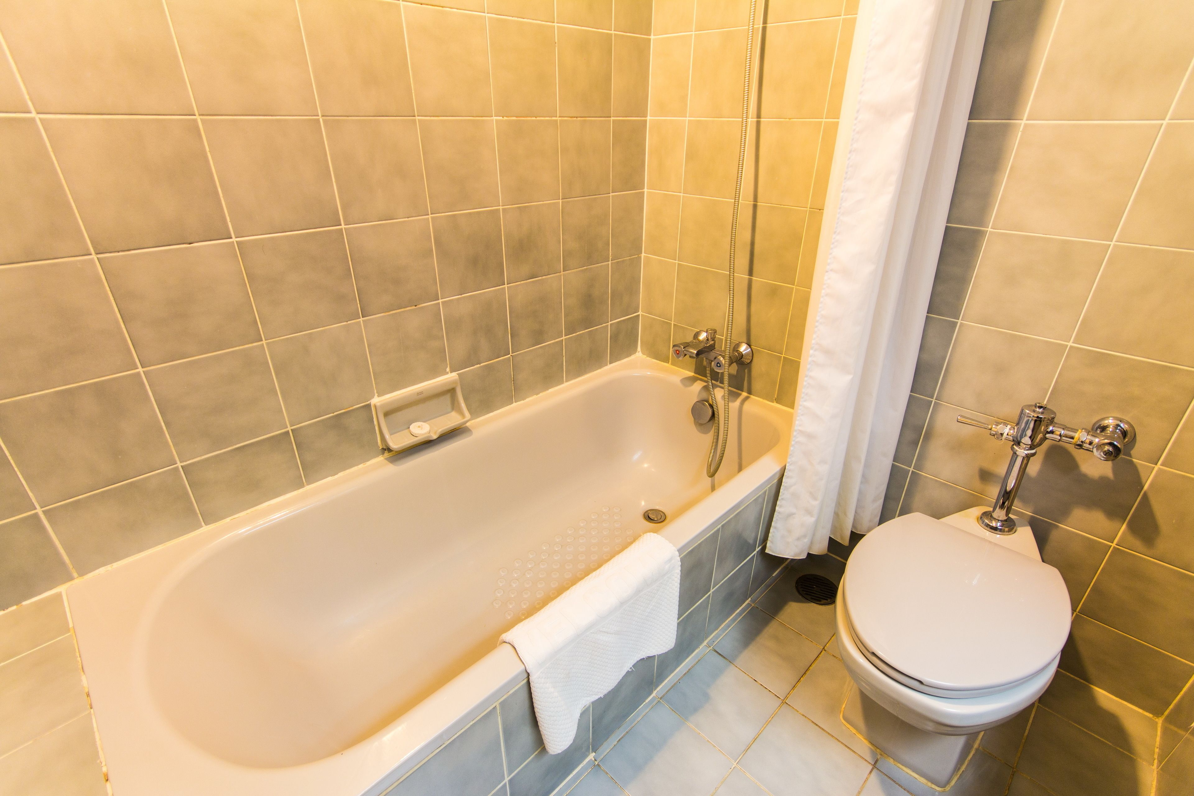 A bathroom with a bathtub, toilet, and tiled walls.