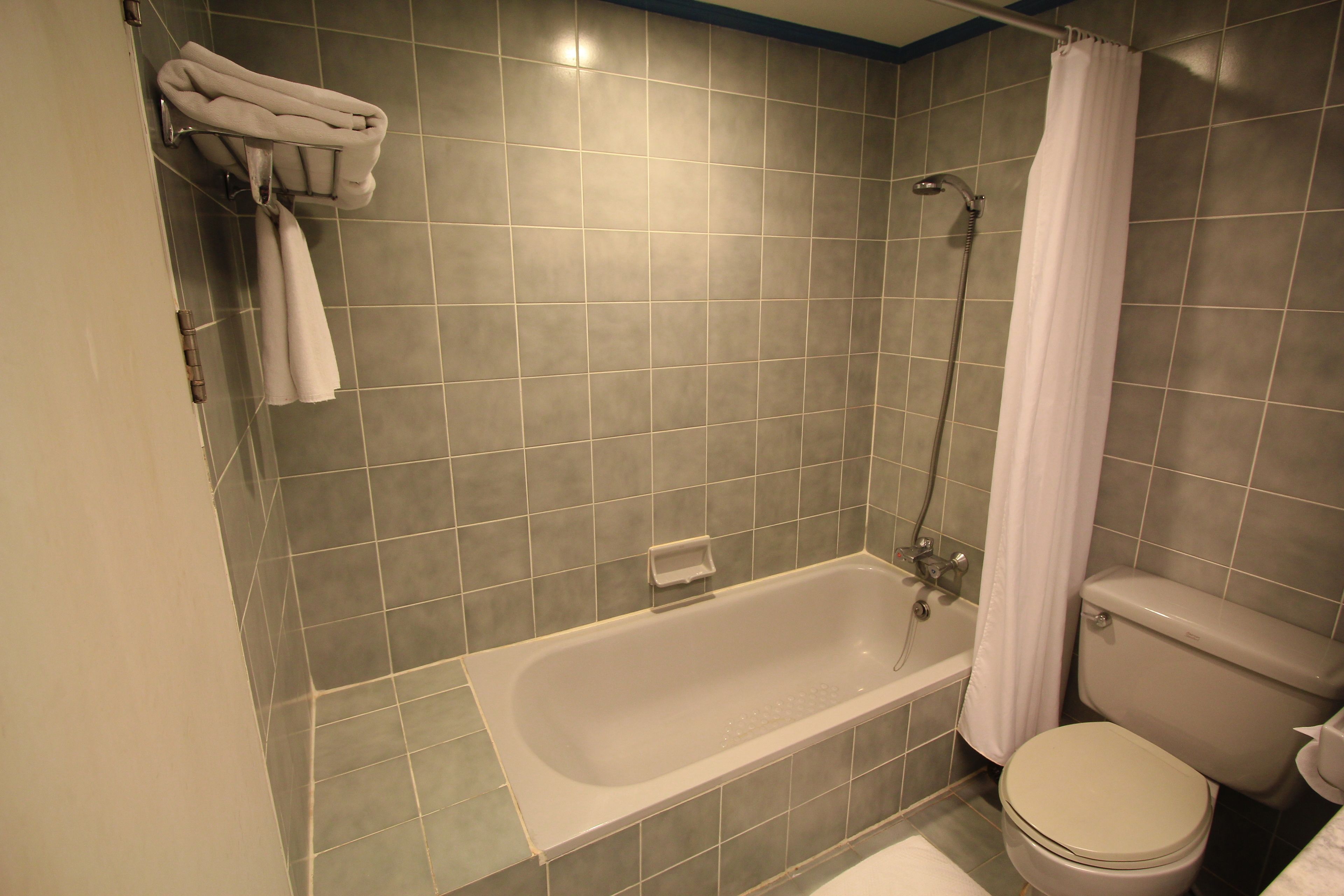 A bathroom with a bathtub, toilet, and a towel rack with towels.
