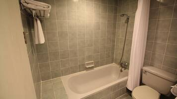 A bathroom with a bathtub, toilet, and a towel rack with towels.