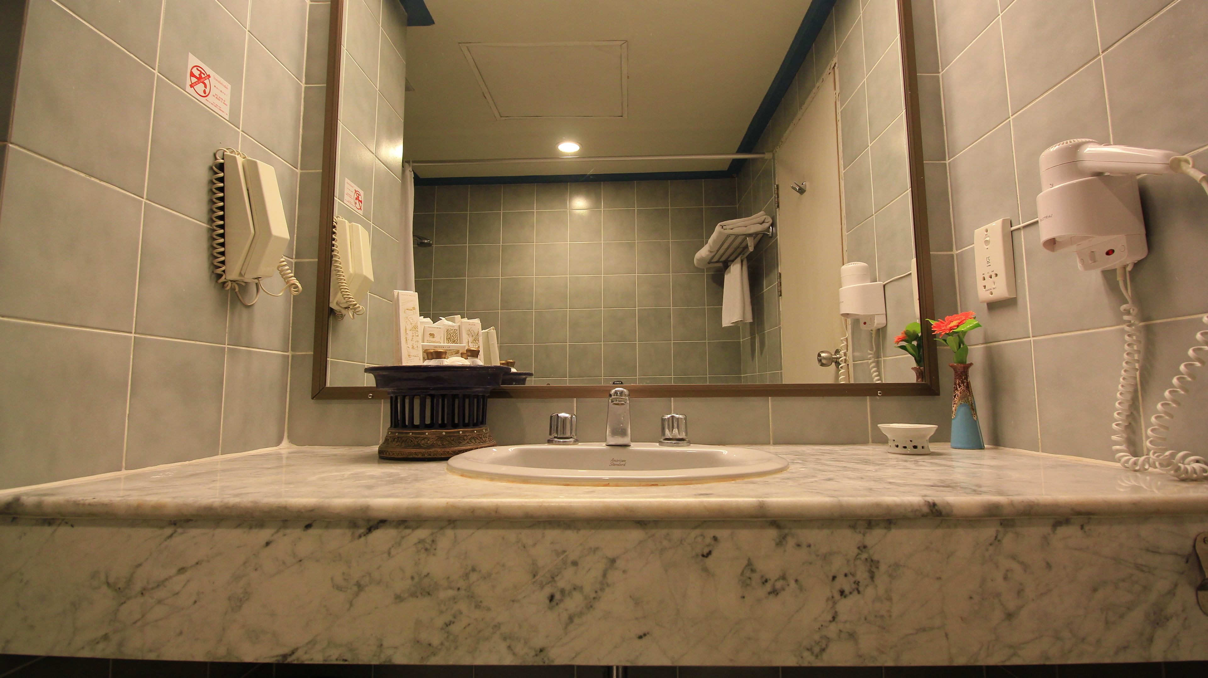 A bathroom with a marble sink, a mirror, a hairdryer, and a telephone.
