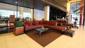 A modern lobby with a sectional sofa, a glass coffee table, and a red accent wall. - Chiang Mai Hill (Chiang Mai)