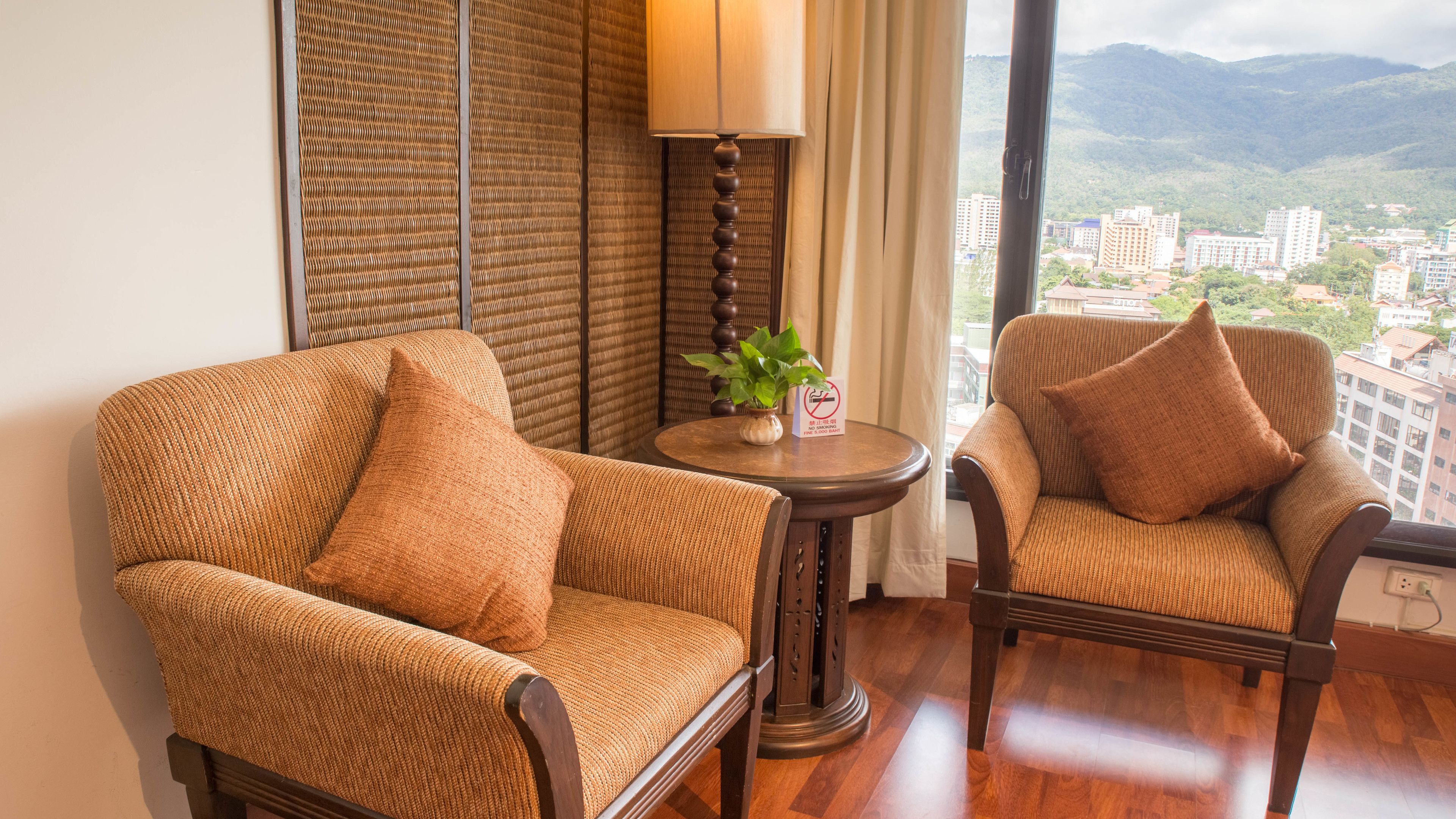 Two wicker armchairs with cushions, a small round table with a plant, and a lamp.