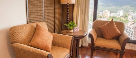 Two wicker armchairs with cushions, a small round table with a plant, and a lamp.