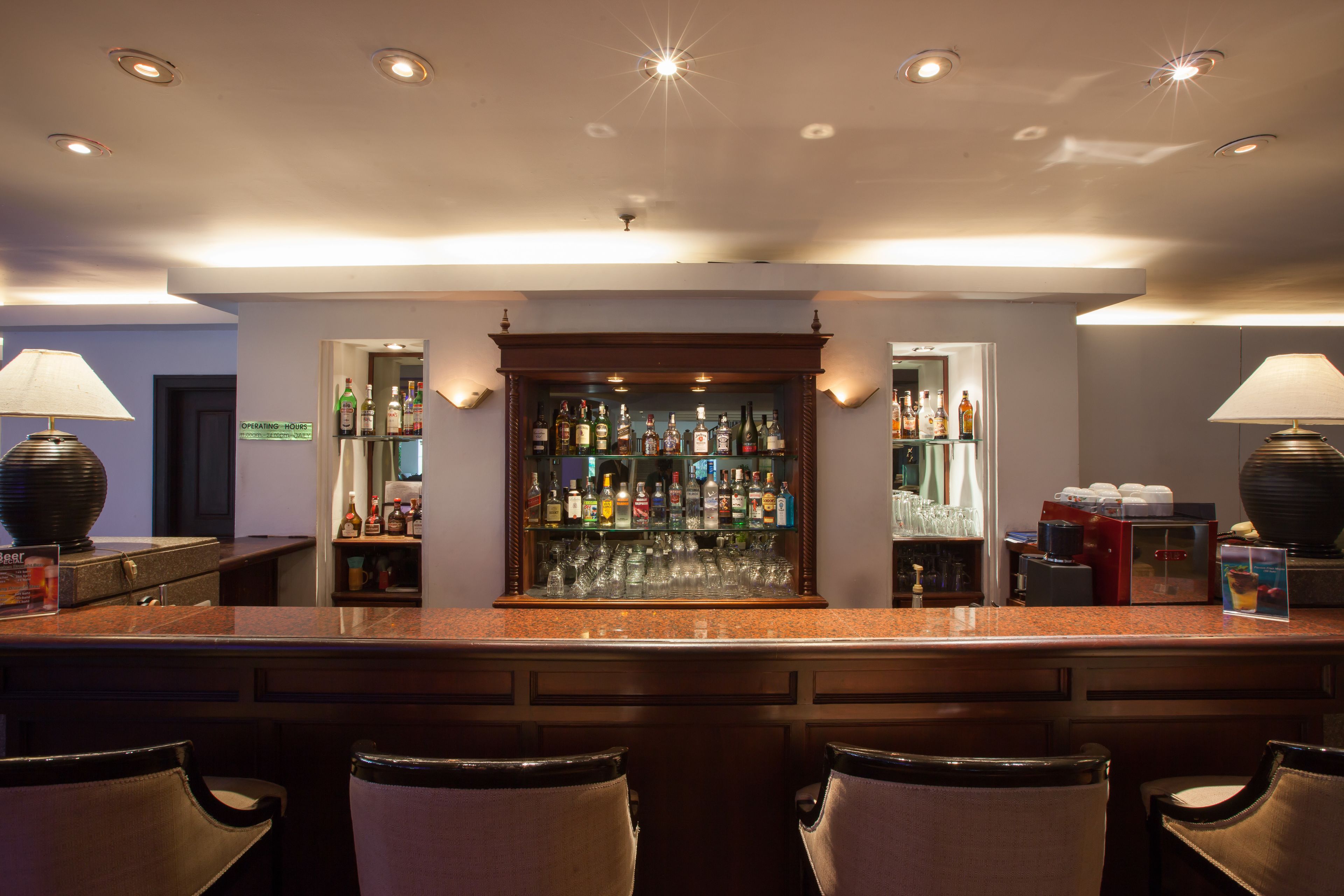 A bar area with a long counter, multiple seating options, and a well-stocked liquor shelf.