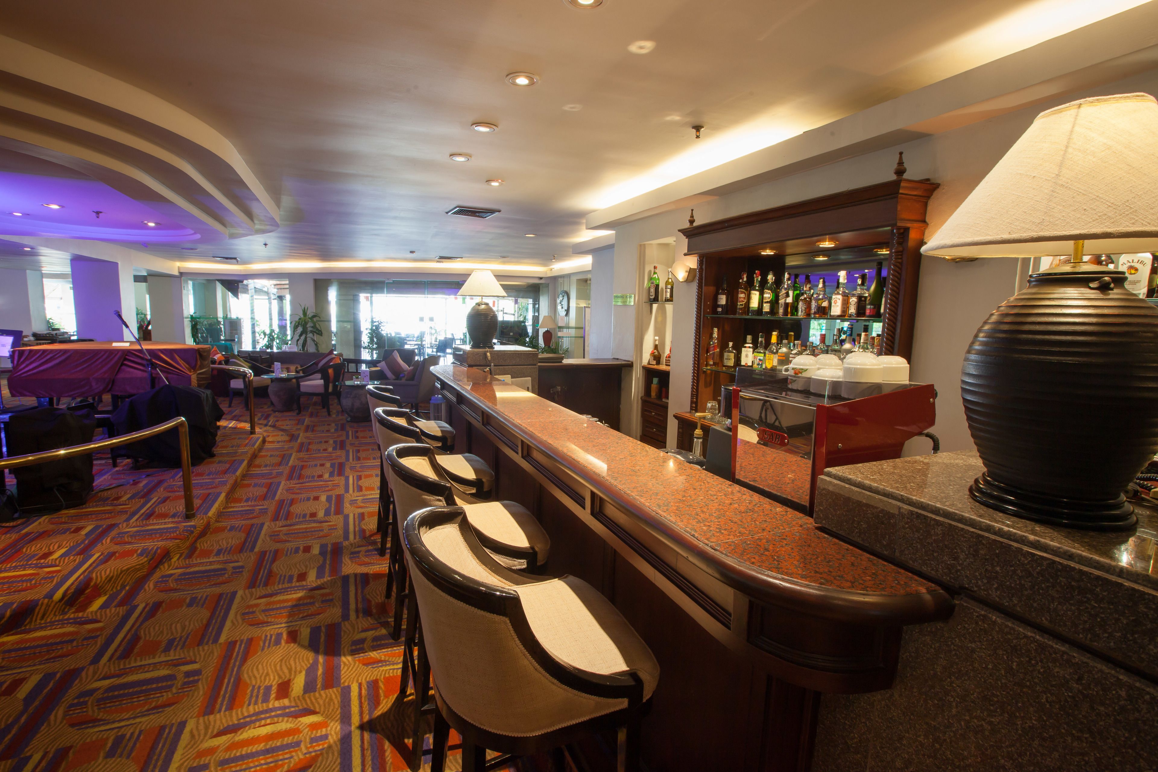 A hotel lobby with a bar area, seating, and a view of the outdoors.