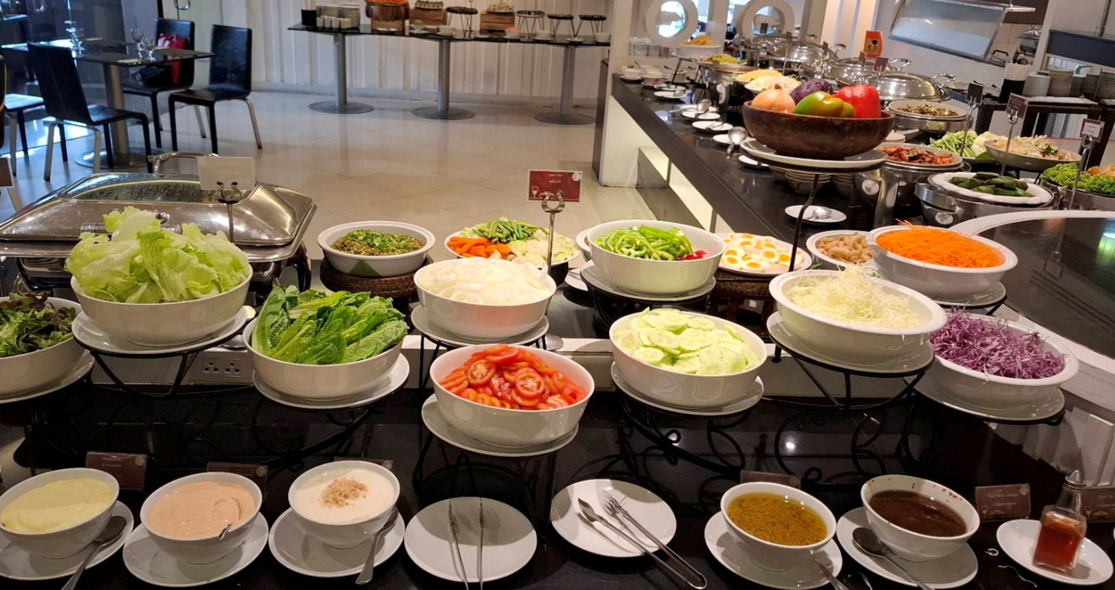 A buffet with various food options including salads, vegetables, and sauces.