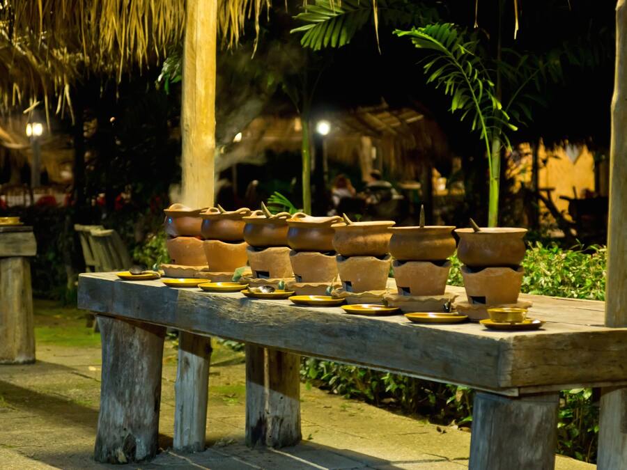 Una mesa de madera con macetas de terracota y platos, dispuesta al aire libre por la noche.
