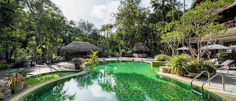 Una piscina al aire libre, sombrillas, sillones reclinables de piscina