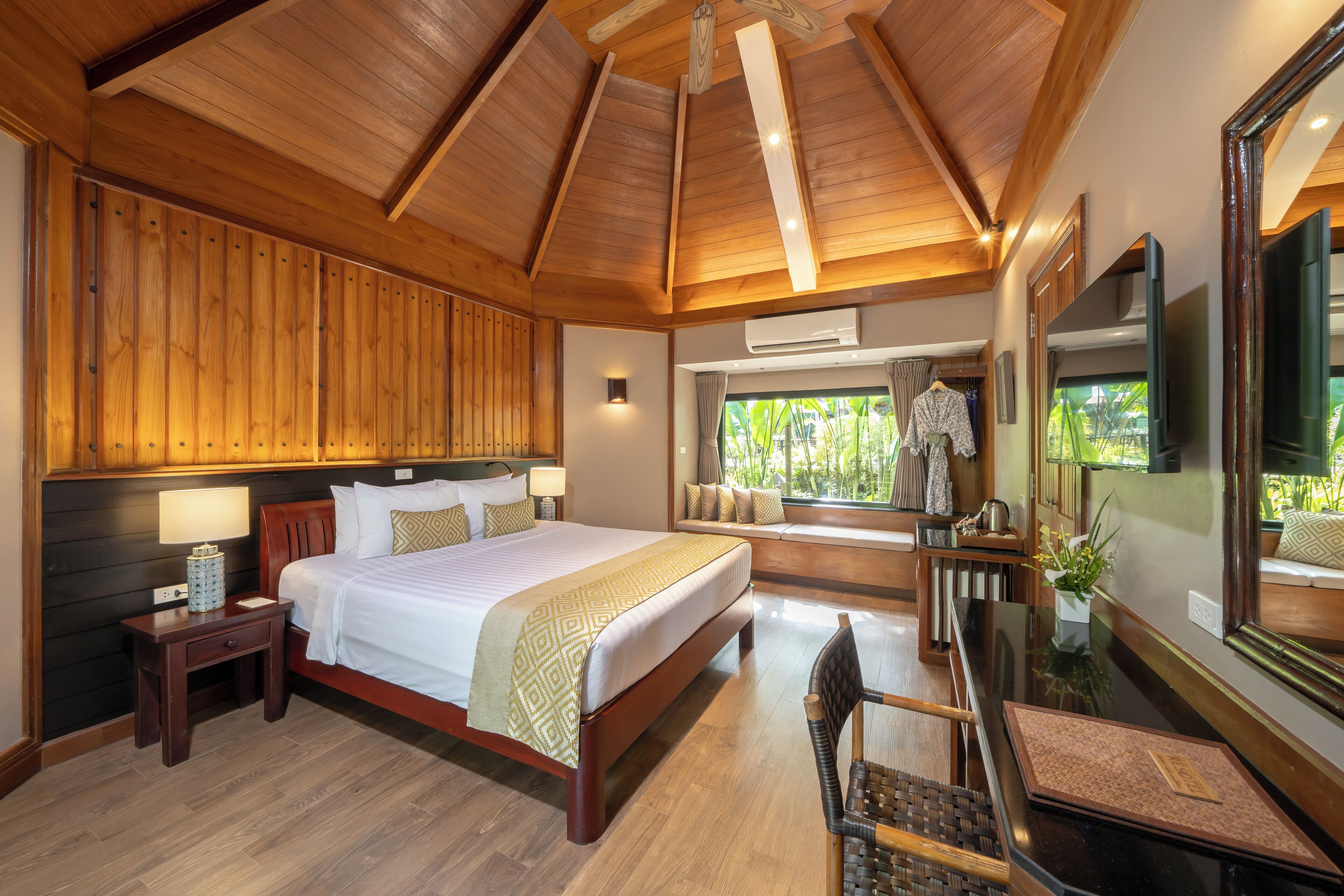Une chambre spacieuse avec un grand lit, un plafond en bois et une vue sur la verdure par la fenêtre.
