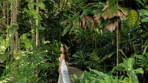 Una mujer caminando por un sendero rodeado de exuberante follaje tropical.