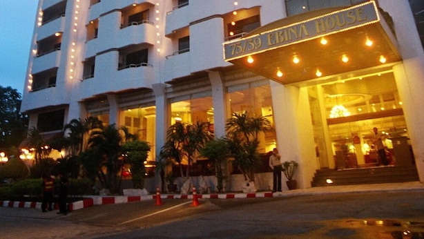 Um hotel de vários andares com design moderno, apresentando uma entrada destacada com uma placa, várias varandas e fachada bem iluminada.