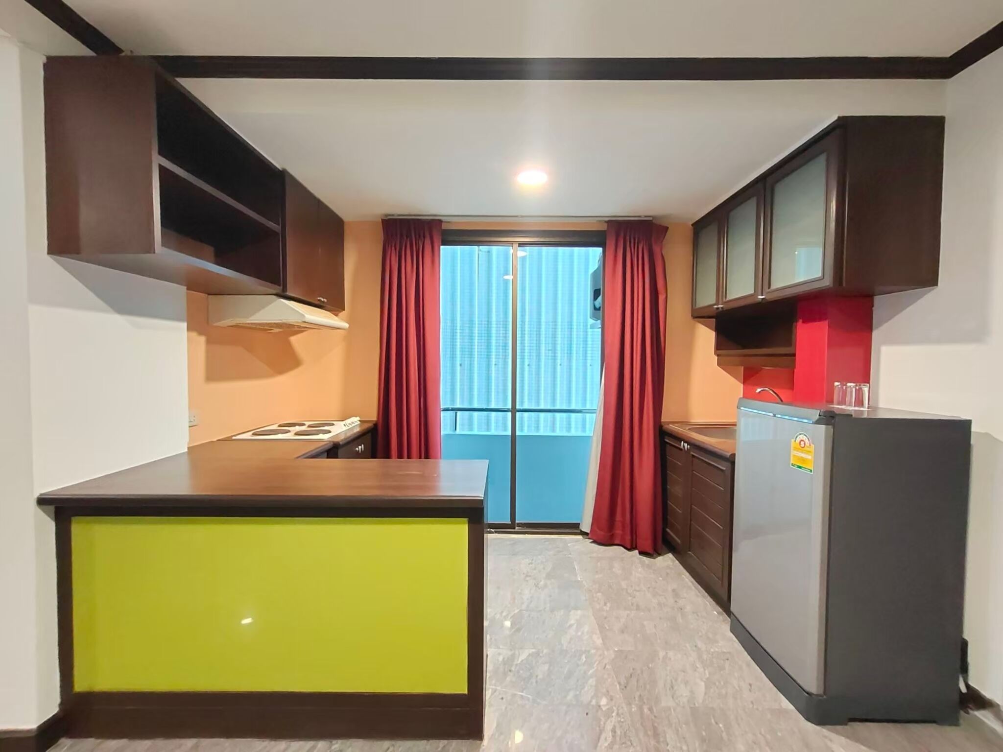 A compact kitchen with a built-in stove, a refrigerator, and cabinets.