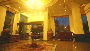 Um hall amplo com lustre, área de estar e grandes janelas.