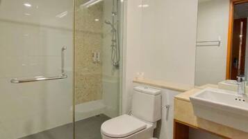 A modern bathroom with a glass-enclosed shower, a toilet, and a sink with a mirror above it.