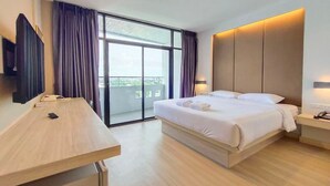 Quarto de hotel moderno com uma cama grande, escrivaninha, televisão de tela plana e varanda com cortinas.