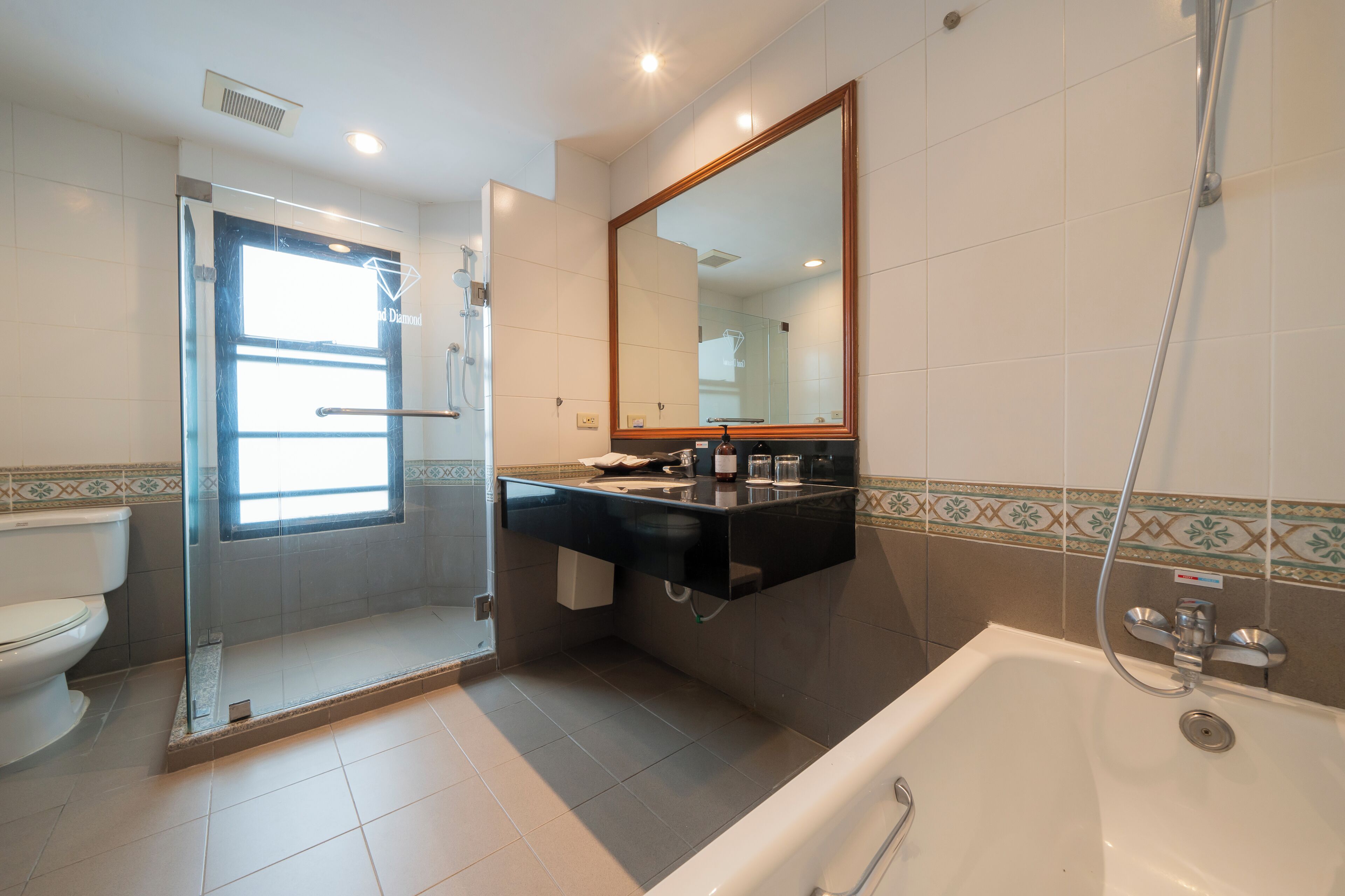 A bathroom with a toilet, a shower, a sink with a mirror, and a bathtub.